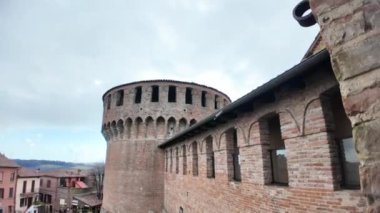 Ortaçağ duvarları üzerinde bulutlu bir gökyüzü ve İtalya 'nın Emilia Romagna kentindeki Dozza köyünde yer alan Rocca Sforzesca di Dozza' nın dairesel kulesi.
