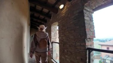 Ortaçağ kalesi Dozza, Emilia Romagna 'daki dairesel bir odadan manzaraya hayran olan kadın turist, tuğla duvarlar, ahşap tavan ve büyük pencerelerle donatılmış.