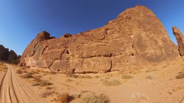 Suudi Arabistan 'daki Alula Sharaan Doğa Koruma Alanı' ndaki yüksek kumtaşı oluşumları boyunca toprak bir yolda giden off road aracı. Çarpıcı bir çöl manzarasında macera ruhu yakalamak. Hava görünümü