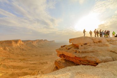 Tuwaiq, Suudi Arabistan - 11 Ocak 2025: Günbatımında dünyanın bir ucundan gelen turistler, Riyad, Suudi Arabistan 'daki Tuwaiq dağ sırasının uçurumlarını düşünüyorlardı.