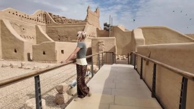 Sarışın turist, bölgenin zengin kültürel mirasını keşfeden Suudi Arabistan 'ın Riyad yakınlarındaki antik Diriyah kentinin kalıntılarına bakıyor.