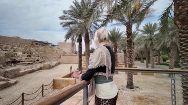 Sarışın turist, etkileyici tarihi Diriye harabelerinde, Suudi Arabistan 'ın Riyad kenti yakınlarındaki UNESCO Dünya Mirası sahasında, güzel mavi bir gökyüzünün altında, bazı bulutlarla birlikte.