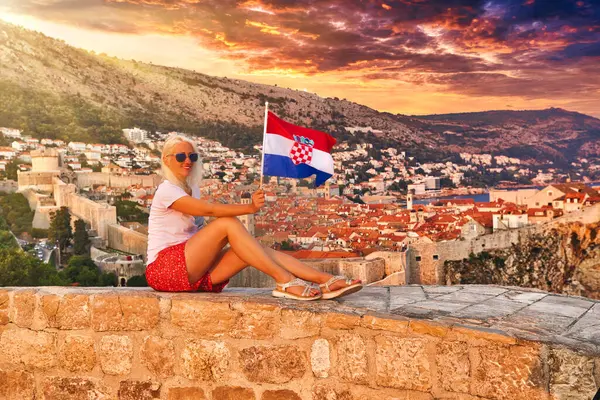 Hırvatistan 'ın Lovrijenac kalesinde arkasında Bokar Kalesi olan bir kadın Hırvat bayrağını taşıyor. Dubrovnik, UNESCO 'nun Dünya Mirası Bölgesi ve Dalmaçya' nın eski bir Venedik kenti olan Hırvatistan 'dır..
