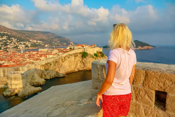 Fort Lovrijenac kalesinden Dubrovnik 'in silueti görünen bir kadın. Hırvatistan 'ın Dubrovnik Batı Limanı' nda. Dubrovnik tarihi şehri ve Bokar Kalesi manzarası. Hırvatistan 'ın Avrupa' daki Dalmaçya tatili