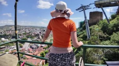 Güneşli bir günde, Tiflis, Georgia 'nın göz kamaştırıcı panoramik manzarasının keyfini çıkaran, yaz kıyafetli bir turist.