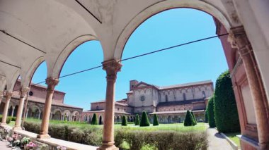 İtalya, Ferrara 'da güneşli bir yaz gününde, yeşil çimenli, mavi gökyüzü ve manastır kemerleriyle çerçevelenmiş, Ferrara Charterhouse of Ferrara Kilisesi.