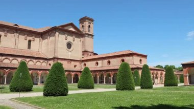 Ferrara Charterhouse Aziz Christopher Kilisesi, eşsiz bir Cotto tuğla cephe, bereketli yeşil çimenler ve ağaçlar arasında açık mavi bir gökyüzü altında görkemli bir şekilde yükselir