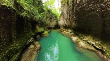 Bereketli yeşillikler ve yüksek kaya oluşumlarıyla çevrili Georgia 'daki Martvili Kanyonu' ndan akan sakin turkuaz su nefes kesici bir doğal manzara yaratır.