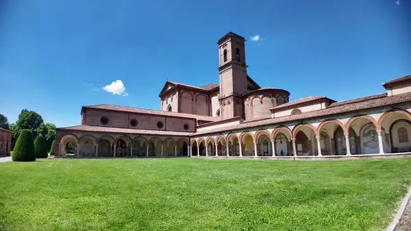Ferrara, İtalya - 17 Mayıs 2025: Açık mavi gökyüzü altında yemyeşil çimenler arasında bir kilise, çan kulesi ve manastır bulunan Ferrara Çartır evini geniş açı görüşü