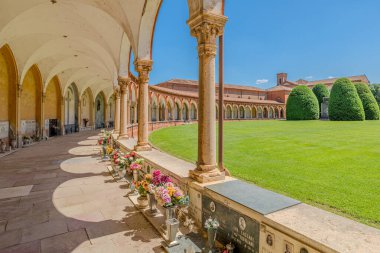 Ferrara, İtalya - 17 Mayıs 2025: Geniş açı görüntüsü, Ferrara Çartır evinin görüntüsü, manastır kemerli geçidi, çan kulesi açık mavi gökyüzü altında yemyeşil çimlerin arasında