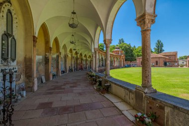 Ferrara, İtalya - 17 Mayıs 2025: Ferrara Manastırı 'nın geniş açılı görüntüsü, yeşil çimen ve selvi ağaçları çerçeveli sütun ve kemerlerin yer aldığı