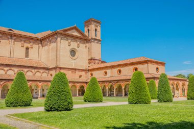 Güneşli bir günde manastırı ve cephesi olan Ferrara 'daki Aziz Christopher Kilisesi, İtalya' nın Ferrara şehrinde manikürlü çimenler ve koni biçimli çalılarla çevrilidir.