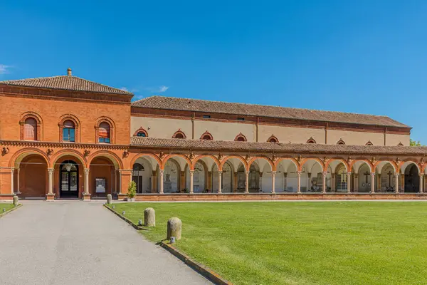 Ferrara, İtalya - 17 Mayıs 2025: Ferrara, İtalya Charterhouse 'un büyüleyici mimari güzelliğini deneyimleyin, parlak mavi gökyüzü altında zarif kemerlerini ve huzurlu bahçe manzaralarını sergiliyor