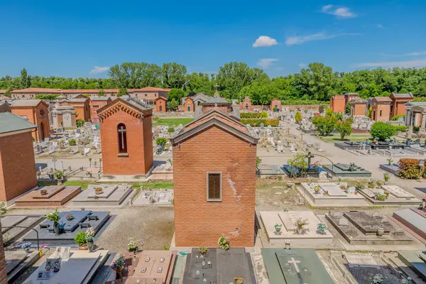 Ferrara, İtalya - 17 Mayıs 2025: Mezarlar, büyük bir kırmızı tuğla duvar ve küçük bir şapel, Ferrara Çartır 'ın anıtsal mezarlığı berrak mavi bir gökyüzü altında huzur yayar.