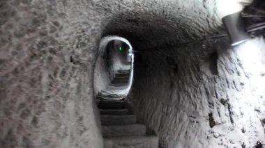 Orta Çağ boyunca Eruşeti kayalıklarına oyulmuş antik bir mucize olan Vardzia mağara manastırının derinliklerine doğru uzanan taş adımlar kaba yontulmuş duvarları ortaya çıkaran tek bir ışıkla aydınlatılıyor.