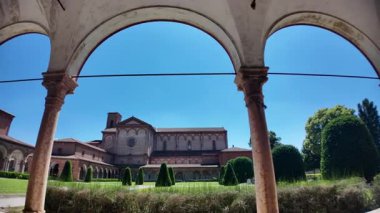İtalya, Ferrara 'da güneşli bir yaz gününde, yeşil çimenli, mavi gökyüzü ve manastır kemerleriyle çerçevelenmiş, Ferrara Charterhouse of Ferrara Kilisesi.