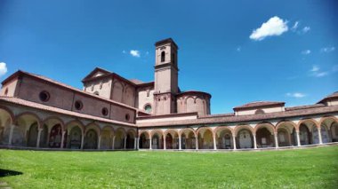 Ferrara Charterhouse 'daki Aziz Christopher Kilisesi, berrak mavi gökyüzünün altında yüksek bir çan kulesinin yanında zarif kemer ve sütunlarıyla çarpıcı bir Rönesans verandasına sahiptir.