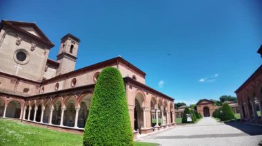 Ferrara 'nın Charterhouse' u içinde yükselen Aziz Christopher Kilisesi 'nin ılık tuğlaları parlak mavi gökyüzünün altında parlıyordu. Mimari güzelliğin huzurlu bir manzarasını yaratıyordu.