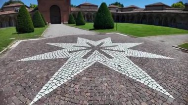 Beyaz ve kırmızı kaldırım taşlarından oluşan sekiz köşeli yıldız mavi gökyüzünün altındaki Ferrara Charterhouse kompleksindeki Aziz Christopher kilisesinin anıtsal mezarlığının avlusunu süslüyor.
