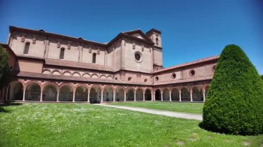 Ferrara Charterhouse 'daki Aziz Christopher Kilisesi, berrak mavi gökyüzünün altında yüksek bir çan kulesinin yanında zarif kemer ve sütunlarıyla çarpıcı bir Rönesans verandasına sahiptir.