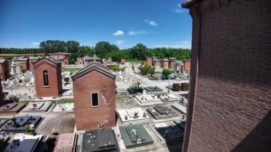 Ferrara Mezarlığı 'nın havadan görünüşü, güneşli bir yaz günü mavi gökyüzü ve üzerinde haç ve eski bina bulunan mezarları gösteriyor.