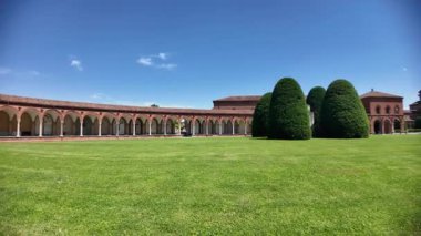 Ferrara, İtalya - Mayıs 2025: 15. yüzyılda San Cristoforo kilisesi ile yemyeşil çimlere karşı inşa edilen Ferrara Charterhouse 'da asılı lambalar, mezarlar ve heykellerin yer aldığı antik mezarlık manastırı