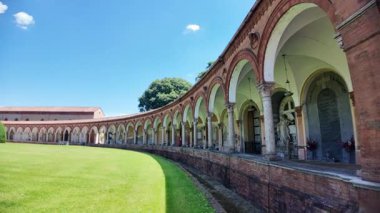 Ferrara, İtalya - 17 Mayıs 2025: İtalya 'daki Ferrara Çartır Evi' nin anıtsal mezarlığı, açık mavi bir gökyüzü altında yeşil bir çimenliği çevreleyen kavisli bir kapı ve kollara sahiptir.