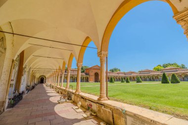 Ferrara, İtalya - 17 Mayıs 2025: Ferrara, İtalya Charterhouse 'un büyüleyici mimari güzelliğini deneyimleyin, parlak mavi gökyüzü altında zarif kemerlerini ve huzurlu bahçe manzaralarını sergiliyor