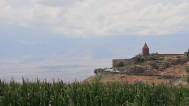 Khor Virap manastırı, arka planda Ararat Dağı olan bir tepede duruyor. Geniş ekili bir tarla ve Ermenistan 'da bulutlu bir gökyüzünün altında nefes kesici bir manzara var.