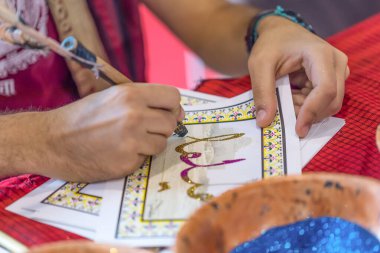 Close-up of a mans hand writing in beautiful handwriting Arabic. Festival of the Orient, 28.09.2019 Brescia, Italy. Editorial. High quality photo