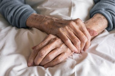Yaşlı bir kadının elleri hastanede bir yatağın üzerinde. Yaşlanma süreci, yaşlı kadınlar. Yüksek kalite fotoğraf
