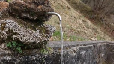 Dağlarda su kaynağı var. Temiz suyun doğal kaynağı yakındır. Su bir borudan dökülüyor. Çevre koruma kavramı. Ağır çekim. Yüksek kaliteli FullHD görüntüler