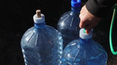 Bir adam dağlardaki doğal bir su kaynağından gelen plastik şişeleri suyla dolduruyor. Dünyada su kıtlığı kavramı. Ağır çekim. Yüksek kaliteli FullHD görüntüler