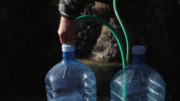Man Fyller Plastflaskor Med Vatten Från Naturlig Vattenkälla Bergen Begreppet — Stockvideo