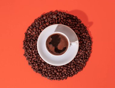 Cup of black coffee and coffee beans in circle on orange background. Minimal horizontal flat lay composition, coffee culture concept