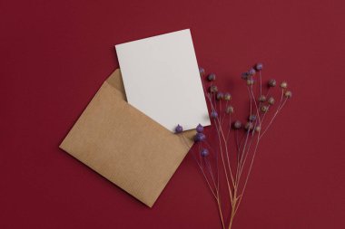 ?raft postal letter decorated with a composition of dried flowers, including dry and painted flax flowers on red background