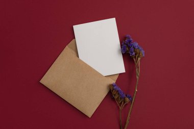 ?raft postal letter decorated with a composition of dried flowers, including purple blooms on red background