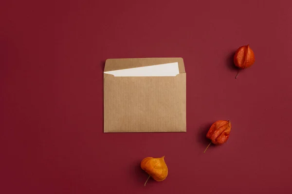 Craft Envelope and Physalis Mockup in Minimalistic Flat Lay on Red Background