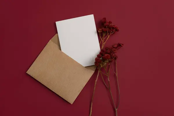 Mockup ?raft postal letter decorated with a composition of dried flowers, including dry red flowers on red background