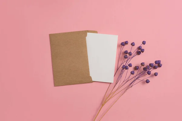 Mockup of a card made from environmentally friendly materials and decorated with a composition of linen branches dyed in purple on a pink background.