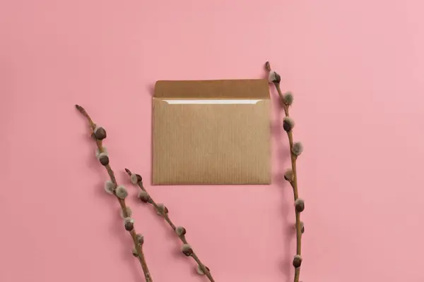 An open greeting card made of kraft paper decorated with blooming branches on a pink background