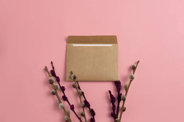 Pembe arka planda çiçek açan kırmızı dallarla süslenmiş kraft kağıdından yapılmış bir kart.