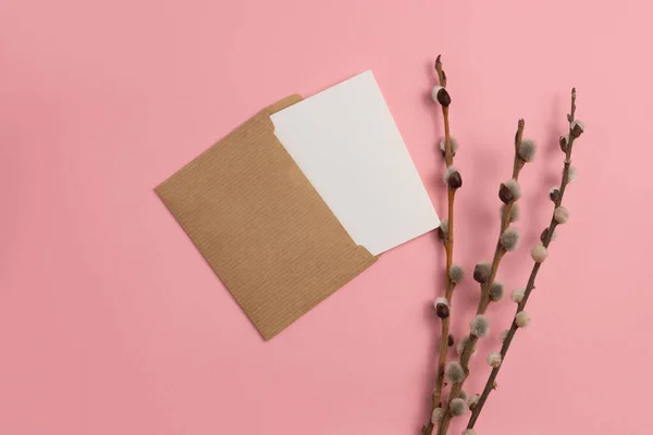 An open greeting card made from environmentally friendly materials and decorated with dried blooming branches on a pink background.