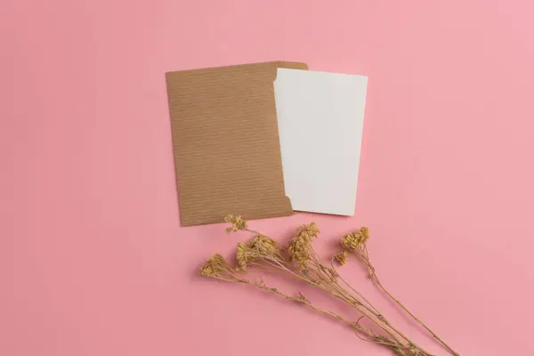 Mockup card made of eco-friendly materials and decorated with dried herbs on a pink background
