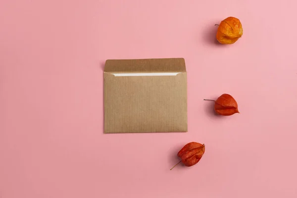 Mockup of a craft paper card with a composition of physalis on a pink background