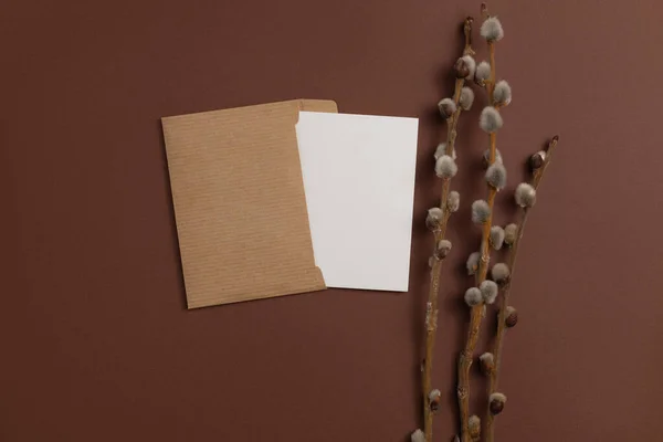 Mockup of an open card made from eco-friendly materials and decorated with a composition of dried flowering branches placed on a brown background