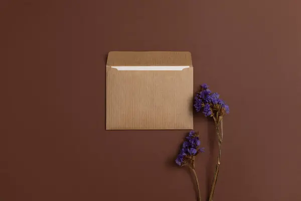 Mockup of a card made from kraft paper and decorated with a composition of dried purple flowers placed on a brown background