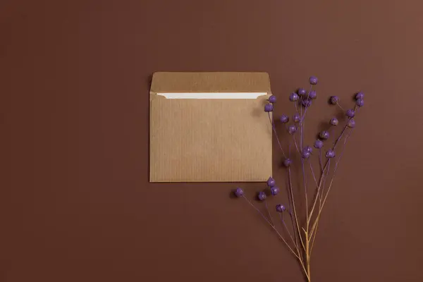 Çevre dostu kraft kağıdından yapılmış ve narin mor renklere boyanmış kurutulmuş keten çiçeklerle süslenmiş ve kahverengi bir arka plana yerleştirilmiş bir kart.