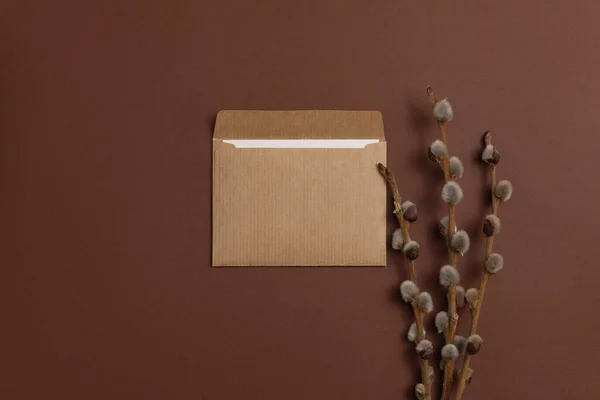 Invitation card made of eco-friendly kraft paper and decorated with a composition of dry blooming branches placed on a brown background