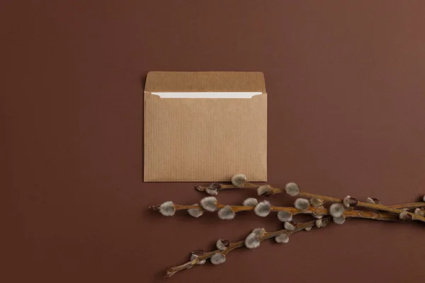 Invitation card made of eco-friendly craft paper and decorated with a composition of dry flowering branches arranged on a brown background in a horizontal orientation
